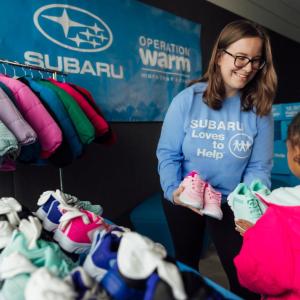 Volunteer handing shoes to child
