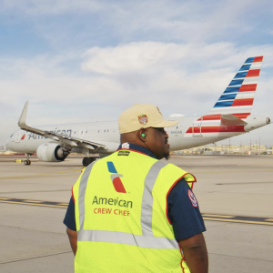 A person stood on an aeroplane runway wearing a hi-vis vest 