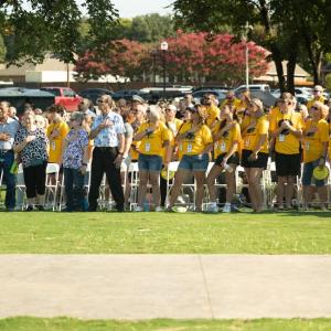 A crowd of people showing their respect by putting their right hand over their heart