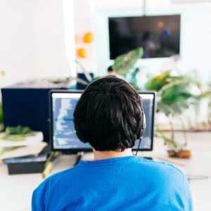 Operator seated behind a desktop computer wearing headphones.