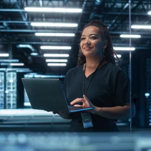 Female holding a laptop in a server room.