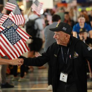 People waving American flags and shaking hands with war veterans
