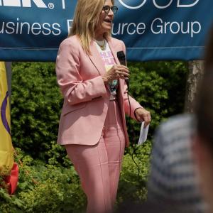 A person speaking to a group, a banner behind them "Kohler Proud".