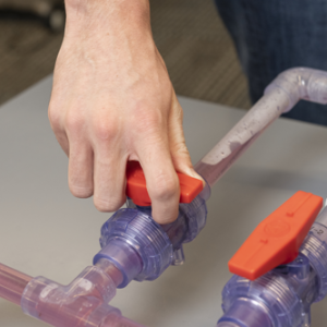 The valve shows dyed water flowing through the pipelines.