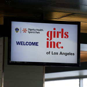 Digital welcome sign at Dignity Health Sports Park displaying LA Galaxy and Girls Inc. of Los Angeles logos ahead of a youth empowerment event.
