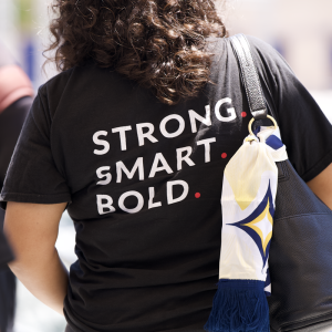 Participant wearing a “Strong. Smart. Bold.” Girls Inc. T-shirt and carrying an LA Galaxy scarf during a youth leadership event at Dignity Health Sports Park.