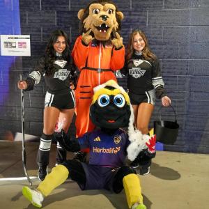 Two LA Kings Ice Crew members pose with costumed mascots wearing LA Kings and LA Galaxy apparel at a Halloween-themed event.