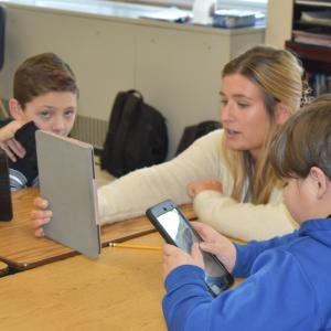 a teacher reads to students from a tablet