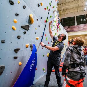 Jesse Kindelberger helps a young explorer navigate the climbing wall at Public Lands.