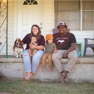 Jahmicah and Heather Dawes seated on their front porch with their two children and dog.