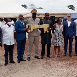 group of people stand in a line. A few hold a giant key