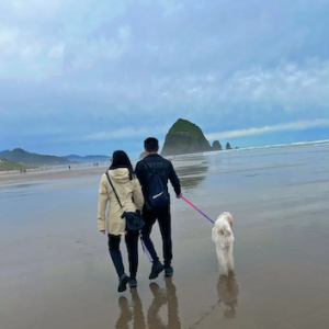 Dannie and another person walking her dog on a beach.