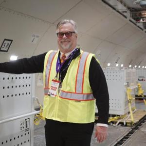 Dave Lange inside the cargo bay of a plane, one hand on a large crate.