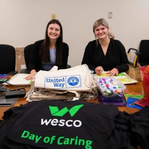 Two people at a table with Wesco Day of Caring shirts on it