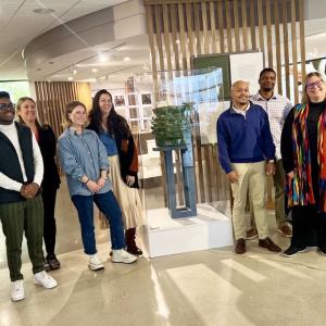 A group of people posed by a sculpture in a gallery.