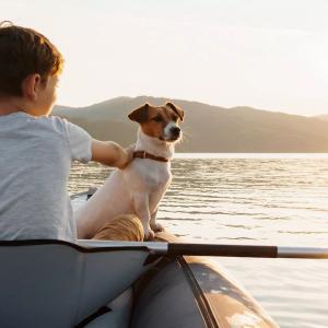 Young boy sitting in a canoe with his dog on a lake.