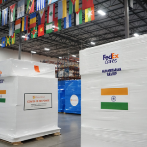 Two large boxes in a warehouse with flag of India on the outside. Many national flags hag from the ceiling.
