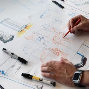 Jonas shown at a drafting table working on design sketches.