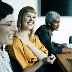 Three people sat a desk laughing 