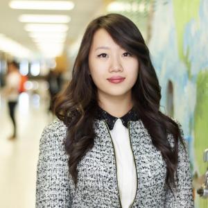 One person standing in a hallway in front of painted lockers