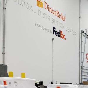 Large bay doors, "DirectRelief Global Distribution Center sponsored by FedEx" on the wall.