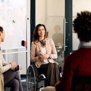 A woman is seated in a wheelchair with three coworkers.