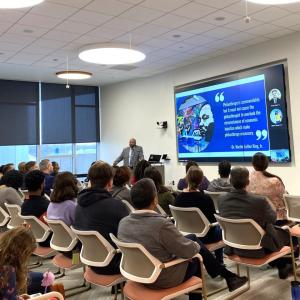 An audience of people sat on chairs facing a project board during an event