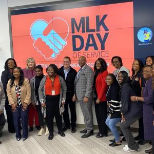 A group of people stood together in front of a projector board that reads "MLK DAY OF SERVICE"