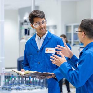 Two people wearing blue lab coats in a lab