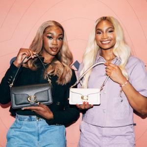 Two people holding up handbags