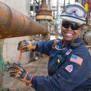Dynita McCaskill turning a valve on an industrial pipe