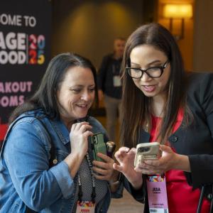 Two conference participants huddled over a cell phone at Engage for Good 2025