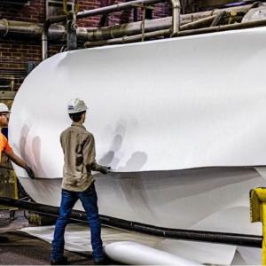 2 factory workers and a large roll of plastic