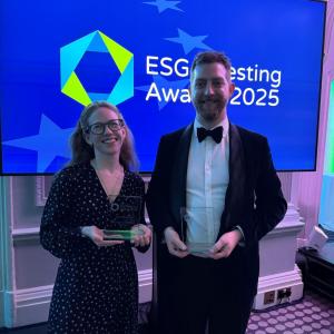 Two people, each holding an award, in front of a screen reading "ESG Investing Awards 2025"