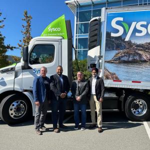 Four people standing by a Sysco semi truck