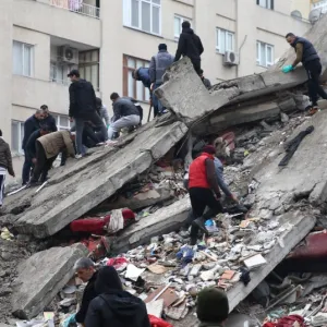 People climbing on top of rubble caused from an earthquake