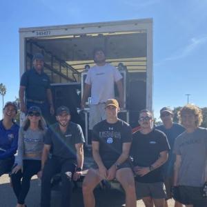 A group of people sitting and standing on the back of an open lorry 