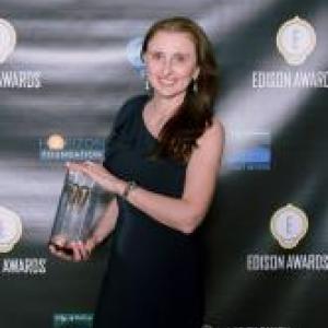 A person holds a trophy in front of a black backdrop with 'Edison Award' logos