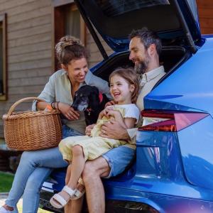 Family of three shown sitting in the back of an EV as it is being charged.