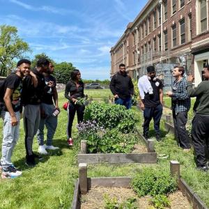 Several people standing around garden beds at Ellen DeGeneres urban farm