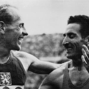 two runners smiling, one with their arm around the other
