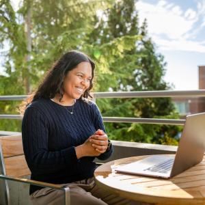 Female employee sitting outside in front of her laptop.