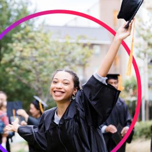 A student wearing a graduation gown, holding up their cap 