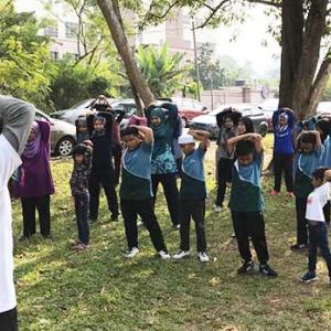 group of about 20 people outside doing stretching exercises 