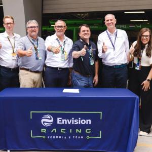 Group standing behind Envision Racing table giving the thumbs up