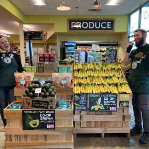 Two workers in a grocery store by banana display