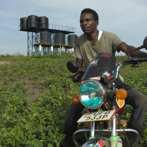 Ernest sitting on his motorized bike in front of his garden.