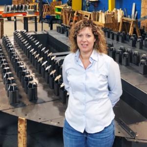 Esther Harper standing in front of neat rows of metal parts