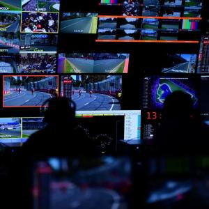 In a dark room people watching multiple monitors.