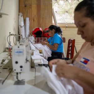 Women sew overalls for other cooperative members.
